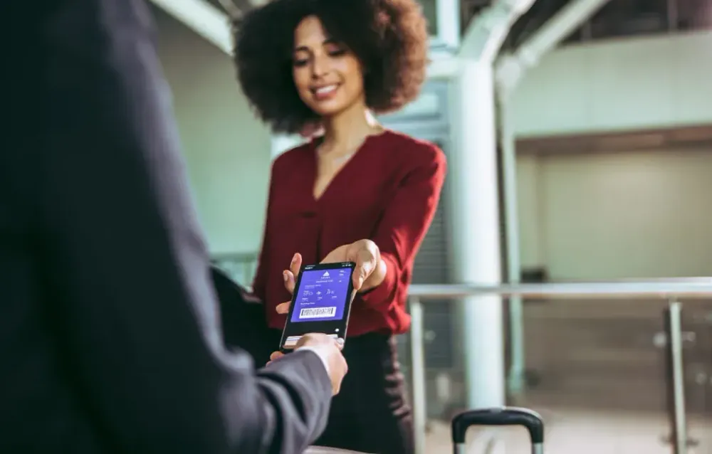 Woman presenting her digital boarding pass on her phone to the gate agent at the airport